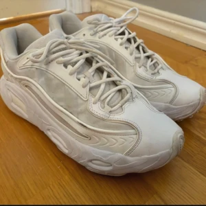 Vita sneakers från Adidas Originals - Snygga vita sneakers från Adidas med adiplus-dämpning. Skorna har en futuristisk design med snörning och en bekväm passform. Perfekta för en stilren look.