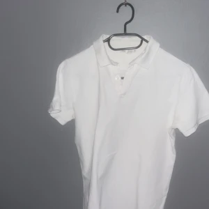 Vit kortärmad pikétröja - Snygg och klassisk vit pikétröja med korta ärmar och krage. Perfekt för en stilren look. Passar både till vardags och mer uppklädda tillfällen.