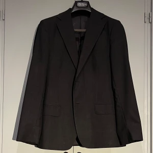 Mörkgrå kostym från Oscar Jacobson - Elegant mörkgrå kostym från Oscar Jacobson i klassisk design med stilren look.  Kostymen har en snygg passform och är tillverkad i ullblandning. Skick 7/10