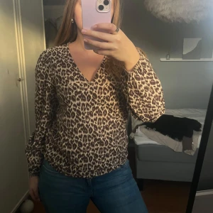 Leopardmönstrad blus - Snygg leopardmönstrad blus med v-ringning och längre ärmar. Perfekt för att ge en trendig touch till din outfit.