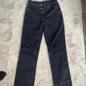 Svarta jeansbyxor från ASOS - Snygga svarta jeansbyxor från ASOS med hög midja och knappgylf. Byxorna har en klassisk femficksdesign och är tillverkade i 100% bomull för en bekväm passform. Perfekta för en stilren look. Alldrig använda!