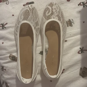 Vita spetsballerinaskor - Eleganta vita ballerinaskor med spetsdetaljer och rund tå. Perfekta för en stilren look. Aldrig använda