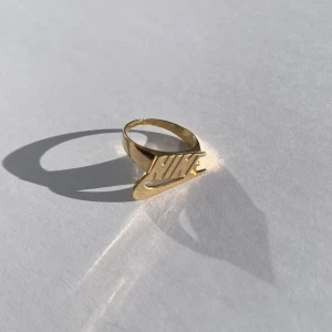 Supreme nike 14k guld ring - Super snygg supreme nike guld ring från ”fall 2019 collection”. 14k guld. Storlek US 9 eller 19mm i diameter. Små skador på påsen men inga skador på själva ringen.