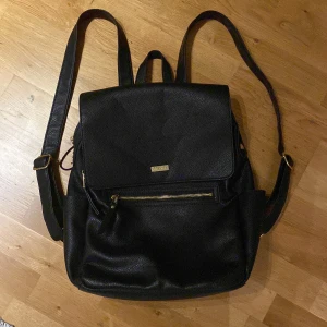 Svart stor ryggsäck - Cool ryggsäck för alla åldrar. Många fickor och rymmer flera böcker, anteckningsblock och dator. Flärpen på en av dragkedjan har gått av (se sista bilden). Köpte den för kanske 300kr