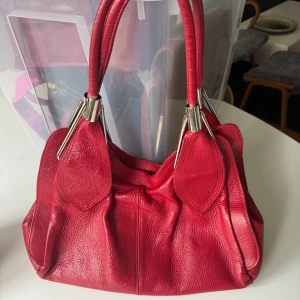 Röd skinnväska från Italien - Säljer en snygg röd kvalitets skinnväska, Borse in Pelle, tillverkad i Italien. Väskan har en cool design med många fack och två dragkedjor. Säljer denna jättebilligt om man jämför på nätet. Hämtas snarast på Hägerstensåsen eller ök. 