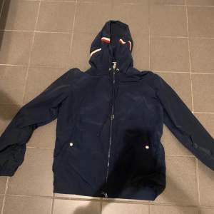 Denna Moncler Wind breaker är perfekt att ha på sommaren men också våren och hösten. Denna är väldigt populär och väldigt snygg. Den är använd 1 gång så är inprincip ny och har inga fläckar eller trasig på något sätt.