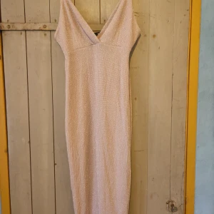 Glittrig beige klänning från Bik Bok - Säljer en superfin glittrig guldbeige klänning från Bik Bok i storlek M. Klänningen är kort och har en elegant v-ringad design. Pretty sexy och juicy.