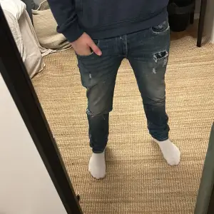 Säljer ett par snygga blå jeans från Replay i bra skick. De har en slim passform och är lite slitna för en cool look. Perfekta för både vardag och fest! 🕺(litet hål i grenen skriv dm för bild)