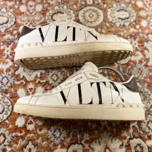 Valentino sneakers med VLTN-logga - Säljer ett par snygga Valentino sneakers i vitt med stor VLTN-logga på sidan. Skorna har snörning och är i bra skick med lite slitage på sulorna. Perfekta för både vardag och fest! 🖤