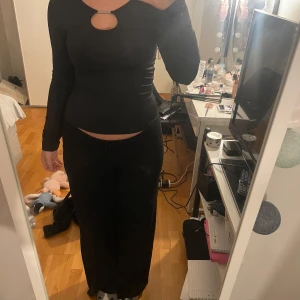 Svart långärmad topp från Weekday - Säljer en svart långärmad topp från Weekday i storlek S. Toppen har en unik design med utskärningar framtill som ger en cool look. Perfekt för både vardag och fest! 🖤