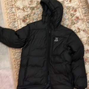 Svart dunjacka från Haglöfs - Säljer en svart dunjacka från Haglöfs i mycket bra skick. Den är perfekt för kalla vinterdagar med sin varma och quiltade design. Jackan har en praktisk huva och dragkedja framtill. Passar både till vardags och utomhusaktiviteter. Storleken är inte angiven, men den ser ut att ha en normal passform. Och så klart kan priset diskuteras 