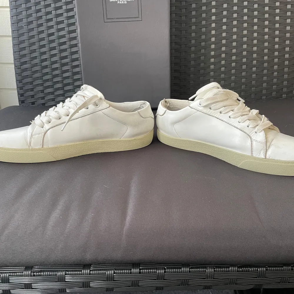 Säljer ett par stilrena vita sneakers från Saint Laurent. Skorna är i bra skick med lite märken framtill. Men fortfarande superfräscha! Kommer med originalkartong. Skick 8/10.  Pris kan diskuteras.. Skor.