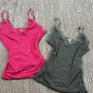 Två ribbade linnen från Amisu - Säljer två snygga ribbade linnen från Amisu i storlek XS. Ett i en härlig rosa färg och ett i en stilren grön nyans. Båda har spetsdetaljer vid halsringningen och justerbara axelband. Perfekta för sommardagar eller som ett lager under en tröja.