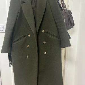 Mörkgrön kappa - Kappa från H&M, använd och lite nopprig men annars i helt skick! Storlek 34 (passar även storlek 36).