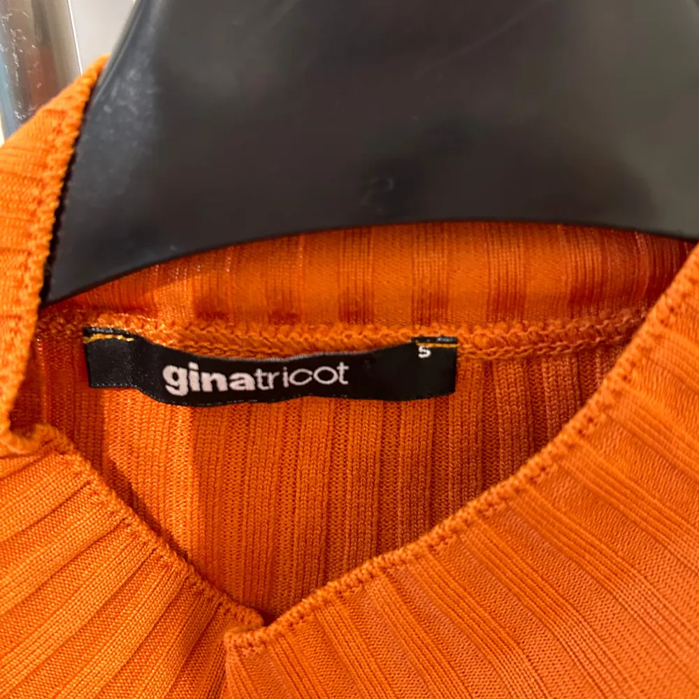 Säljer en snygg orange högkragad långärmad  tröja från Gina Tricot i storlek S. Tröjan har en  cut-out detalj där fram. . Toppar.