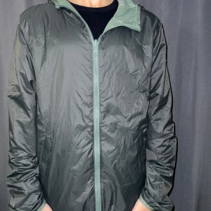 Grön colmar vindbreaker - Säljer en snygg grön vindjacka från Colmar i mycket bra skick. Jackan har en dragkedja framtill och en praktisk huva. Perfekt för vår och höst när vädret är lite ostadigt. Den är långärmad och har en normal passform. Märket syns på ärmen vilket ger en cool detalj.🎧💶