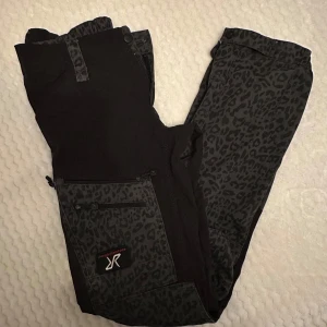 Svarta leopardmönstrade byxor - Säljer ett par coola svarta byxor med leopardmönster. De har en dragkedja och praktiska fickor. Perfekta för en avslappnad stil med en twist. Passar bra till både vardag och fest!