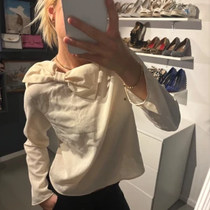 Beige blus med rosett - Säljer en elegant beige blus med en stor rosett vid halsen. 