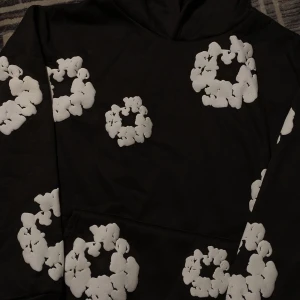 Svart hoodie, Denim Tears - PRIS KAN DISKUTERAS!! Säljer en svart hoodie från Denim Tears med unika vita blommönster. Den är i storlek M och har en klassisk passform med en stor ficka fram. Perfekt för höst och vinter, både stilren och bekväm. 🌼