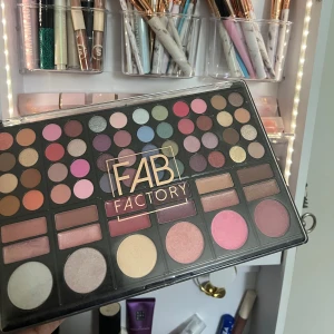 Stor sminkpalett från Fab Factory - Denna sminkpalett från Fab Factory har massor av färgglada ögonskuggor i olika nyanser av rosa, blått, grönt och neutrala toner. Perfekt för att skapa både vardags- och festlooks. Paletten innehåller också rouge och highlighter för en komplett makeup. Perfekt för sminkälskare som vill ha allt i ett!