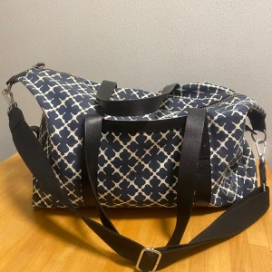 Weekend bag från By Malene Birger - Säljer en snygg väska från By Malene Birger med ett coolt mönster i blått och vitt. Väskan har svarta handtag och axelrem, men det finns lite slitage på handtagen. Insidan är vit med några fläckar. Går att tvätta bort men det har jag tyvärr inte tid till därav priset 💞 Perfekt för träning, skola eller som weekendbag! Priset går att diskutera, pm mig gärna 💞