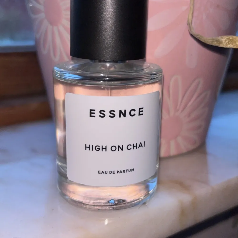 Säljer en flaska Essnce High on Chai Eau de Parfum. Den har en stilren och enkel design med en genomskinlig glasflaska och svart kork. Perfekt för dig som älskar doften av chai och vill ha något unikt i din parfymkollektion.. Parfym.