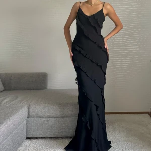 Svart långklänning med volanger - Endast använd en gång! Den är från mango o sälja inte längre hos de och är därmed väldigt svår att få tag på!