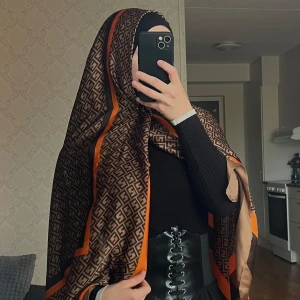 Mönstrad hijab med orange detaljer - Snygg hija  med ett coolt geometriskt mönster i brunt och svart, med orange detaljer som verkligen poppar. Helt ny🤌🏻😍