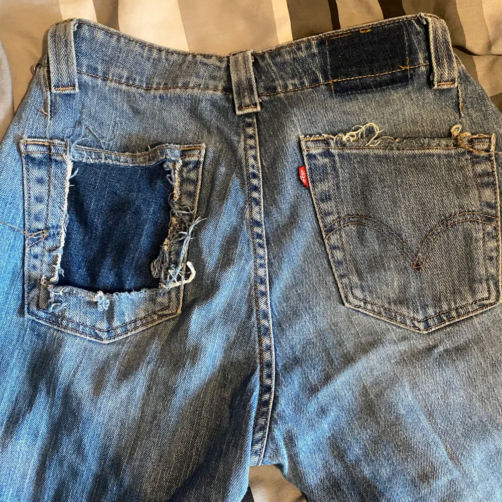 Säljer ett par Levi's Nouveau Low Bootcut jeans i blå denim. De är lågmidjade och har en bootcut-stil. Har endast en bakficka (den andra är utklippt) vilket jag tycker ger en mer unik touch! Jeansen är i bra skick förutom att de är slitna längst ner (se sista bild). Perfekta för en avslappnad stil med sneakers eller boots. Dom för mått! Kan gå med på prisförslag . Jeans & Byxor.