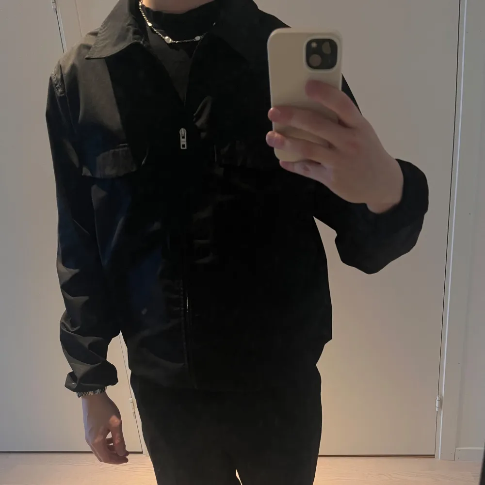 Säljer en stilren svart jacka från Weekday i mycket bra skick. Jackan har en dragkedja framtill och två bröstfickor med lock. Perfekt för höst och vår, och passar till de flesta outfits. Den är långärmad och har en normal passform. . Jackor.