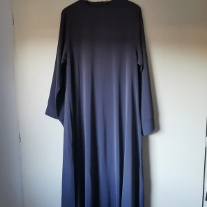 Grå abaya  - Säljer en mörkgrå abaya/klänning i mycket bra skick. Klänningen har en diskret dragkedja i ryggen. Den är gjord i ett mjukt och bekvämt material som faller fint.