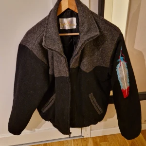 Svart och grå ulljacka med broderi - Säljer en snygg vintage varsity jacka med western tema Perfekt för höst och vinter, med en skön och varm känsla. Passar både till vardags och lite mer speciella tillfällen.