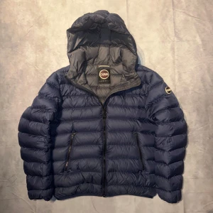 Blå pufferjacka från Colmar - Säljer en snygg blå pufferjacka från Colmar i mycket bra skick. Jackan har en praktisk huva och dragkedja framtill. Perfekt för kyliga dagar och håller dig varm och bekväm. Passar både till vardags och lite mer avslappnade tillfällen. Storleken är M. För mer frågor är det bara att skriva.