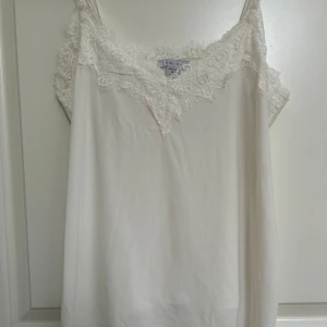 Vit linne med spets - Säljer ett superfint vitt linne från Amisu i storlek S, köpt från new yorker. Det har vackra spetsdetaljer längs halsringningen och tunna axelband. Perfekt för sommardagar eller som ett lager under en kofta.Passar både till vardags och fest! 🌸