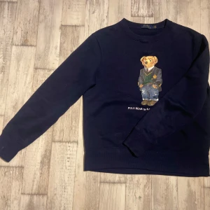 Mörkblå POLO BEAR tröja - Säljer en snygg mörkblå sweatshirt från Ralph Lauren med den ikoniska Polo Bear på framsidan. Tröjan har långa ärmar och är perfekt för en avslappnad stil. Den är i nyskick och passar perfekt för höst och vinter. 🐻💙