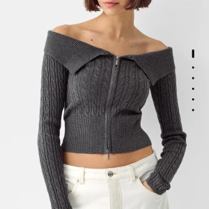 Grå offshoulder stickad tröja - Säljer en superfin grå offshoulder tröja med dragkedja framtill. Den är stickad med ett snyggt kabelmönster och har långa ärmar. Perfekt för höst och vår när du vill vara både stilren och bekväm. Passar bra till både jeans och kjol!
