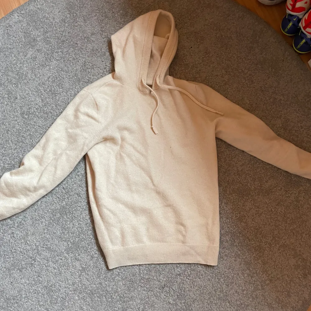 Säljer en snygg beige hoodie i bomull. Den är supermjuk och perfekt för både höst och vår. Tröjan har en normal passform med långa ärmar och en klassisk huva med dragsko. Perfekt för en avslappnad stil!. Tröjor & Koftor.