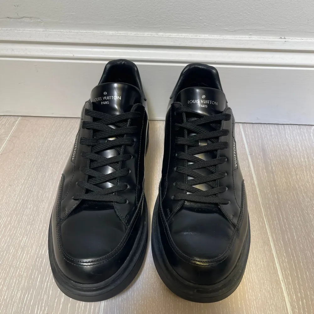 Säljer ett par stilrena svarta sneakers från Louis Vuitton i skinn. De har klassisk snörning och en diskret logga på sidan. Perfekta för både vardag och fest. Skorna är i mycket bra skick och redo för nya äventyr!. Skor.