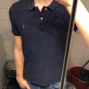 Mörkblå pikétröja från Ralph Lauren - Marinblå polo tröja. Säljer pga har blivit för liten. Passar storlek S perfekt men stor L i tröjan