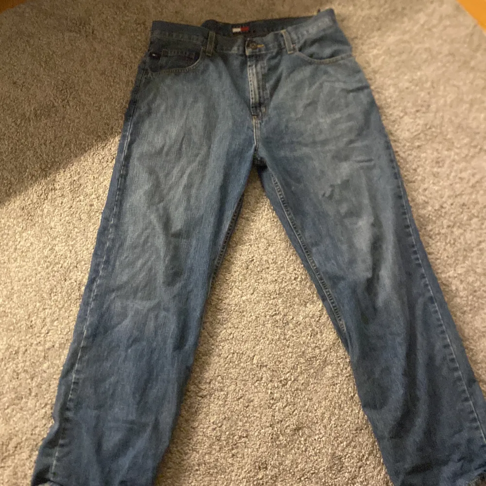 Blåa Tommy Hilfiger byxor som har använts några gånger. Längst ner vid ben öppningen har dem några hål som man kan se i sista bilden annars är de i bra skick.. Jeans & Byxor.