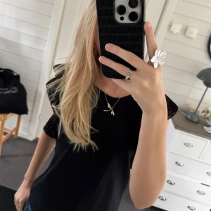 Svart topp med spetsdetaljer  - Säljer en svart topp från H&M i storlek XS. Den har fina spetsdetaljer på ärmarna som ger en elegant touch. Perfekt för både vardag och fest! Toppen är i bra skick och gjord av mjukt material för en bekväm passform.