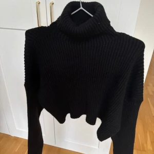 Svart ribbad polotröja från Zara - Säljer en snygg svart ribbad polotröja från Zara. Tröjan är croppad och har långa ärmar, perfekt för en trendig look. Den höga kragen ger extra värme och stil. Passar utmärkt till både jeans och kjol. 🖤 storlek M endast testad 