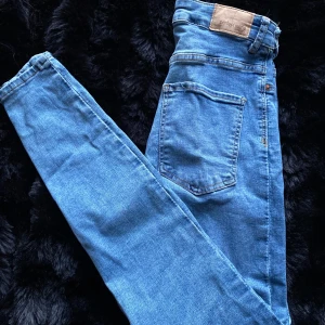 Blå jeans från Gina Tricot - Snygga blå jeans från Gina Tricot i modellen Molly. De har en tight passform och är högmidjade med klassisk femficksdesign. Perfekta för en stilren look.