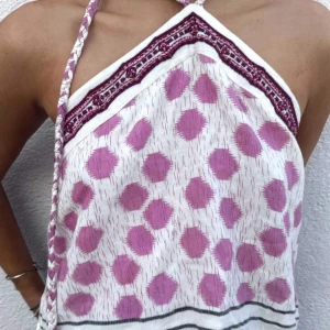 Vit och rosa halterneck-topp - Säljer en söt halterneck-topp i vitt med rosa prickigt mönster. Toppen har en flätad knytning runt halsen och dekorativa broderier i mörkare nyanser längs överkanten. Perfekt för varma sommardagar!