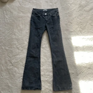 Svarta bootcut jeans - Snygga svarta bootcut jeans med klassisk femficksdesign och knappgylf. Perfekta för en stilren look. Passar bra till både sneakers och klackar.