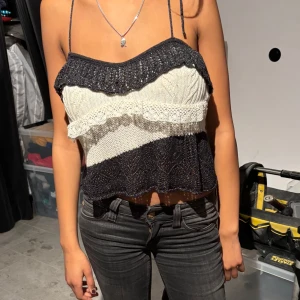 Stickad topp med volanger - Snygg stickad topp med smala axelband och volangdetaljer. Toppen har en randig design i svart och vit med en croppad passform. Perfekt för en trendig look.💘💘💕