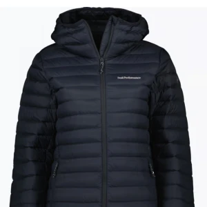 Svart dunjacka från Peak Performance - Säljer en stilren svart dunjacka från Peak Performance. Jackan har en praktisk huva och dragkedja framtill. Perfekt för kyliga dagar med sin quiltade design som håller värmen. En klassisk och funktionell jacka för alla tillfällen. Skriv för egna bilder! Ny pris 3000kr❤️