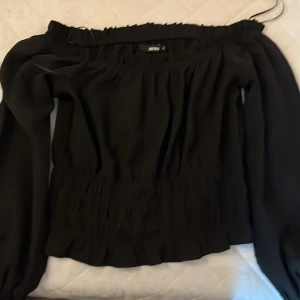 Svart offshoulder topp från BikBok - Snygg svart offshoulder topp från BikBok i storlek XS. Toppen har långa ärmar och en elastisk midja som ger en smickrande passform. Perfekt för att skapa en stilren look.