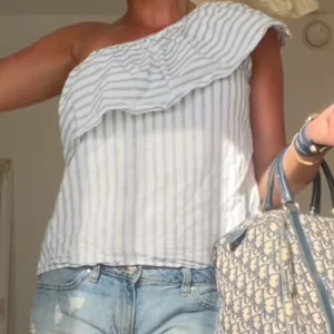 Randig offshoulder topp💗☺️ - Säljer en stilren randig offshoulder topp med volangdetalj. Perfekt för varma dagar och ger en avslappnad men chic look. Passar bra till jeans eller kjol.