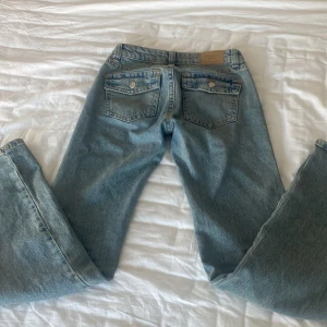 Lågmidjade bootcut jeans från Ginatricot  - Säljer ett par klassiska blå jeans från Ginatricot . De har en bootcut passform med låg midja och är tillverkade i denim med en snygg tvätt. Jeansen har  fickor med knappar bak. Perfekta för en avslappnad stil. Slitna längst ner!! Pris kan diskuteras 